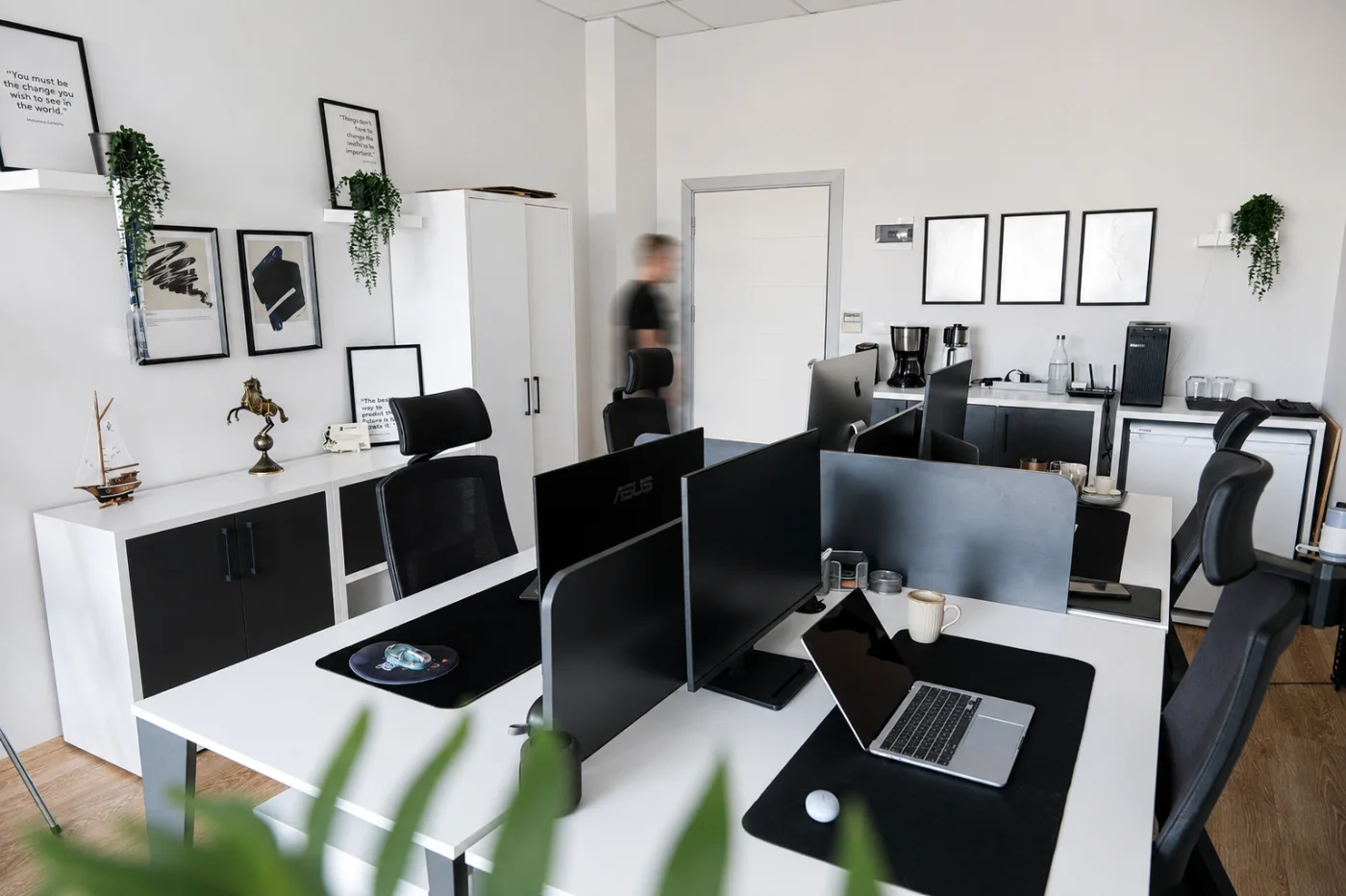 The work area with framed prints on the wall and shared space